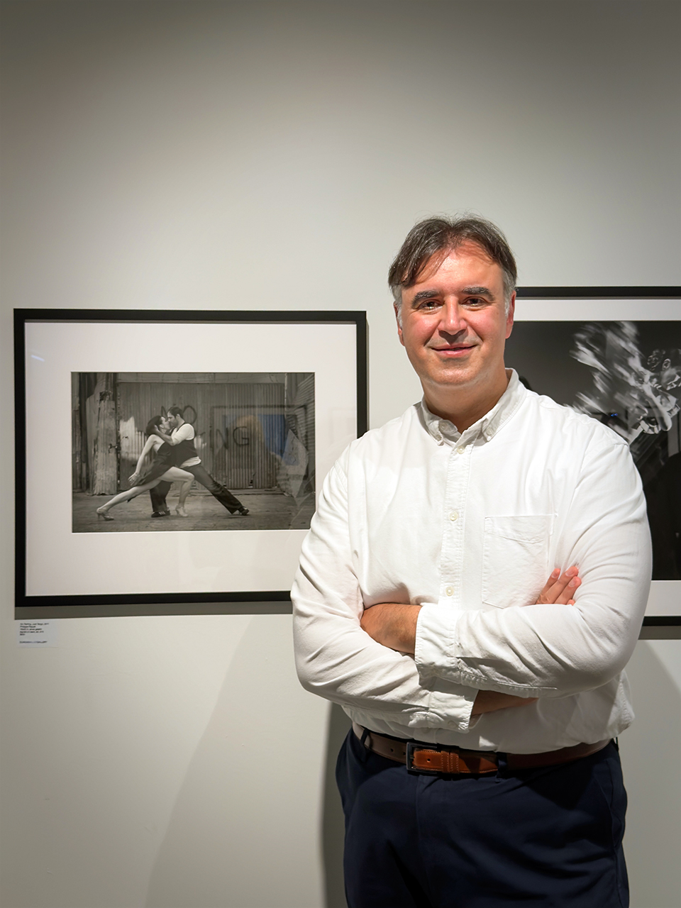 Philippe Paquet beside framed photographs at the DANCE opening reception at Duncan Miller Gallery